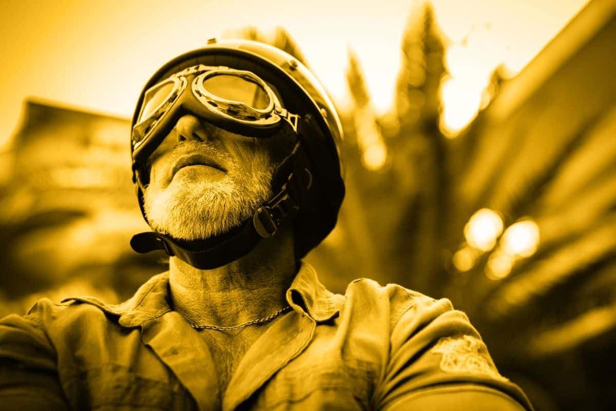 A low-angle photo of an older man wearing a helmet and goggles with a yellow filter.